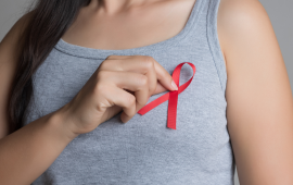 Close up of woman putting a red ribbon pin on her chest