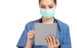 Doctor wearing a mask reading a tablet