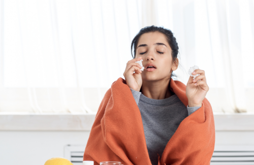 woman about to sneeze and covered with a blanket