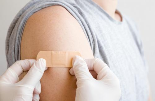 Medical professional putting a band-aid on after giving a vaccine.