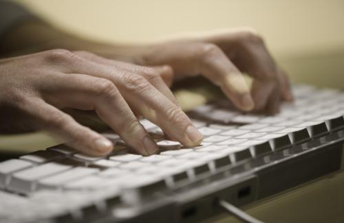 close up of hands typing on white keyboard