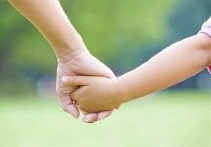 Child and adult holding hands stock photo
