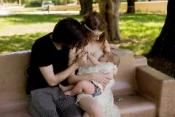 Couple with child breastfeeding on park bench