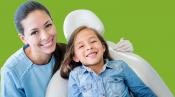 Picture of female dental professional beside a patient sitting in a dental chair smiling