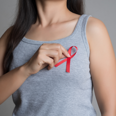 Close up of woman putting a red ribbon pin on her chest