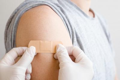 Medical professional putting a band-aid on after giving a vaccine.