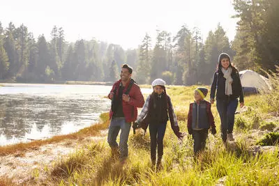 Latino family of four  by lake and trees